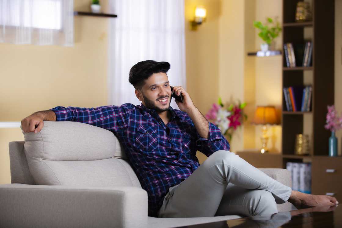 A man relaxes on the sofa as he talks on the phone A man relaxes on the sofa as he talks on the phone