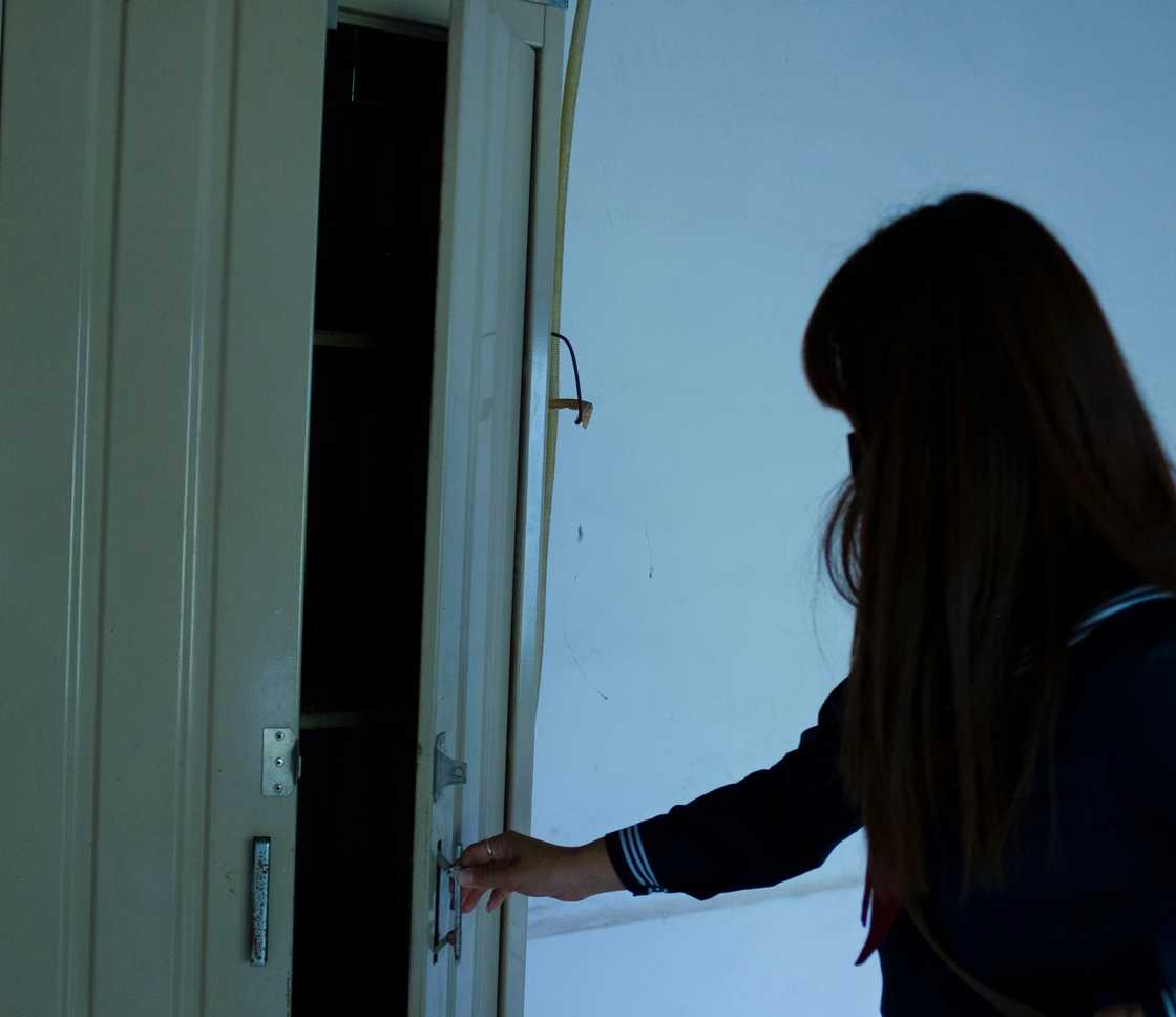A shocked woman standing next to an open door
