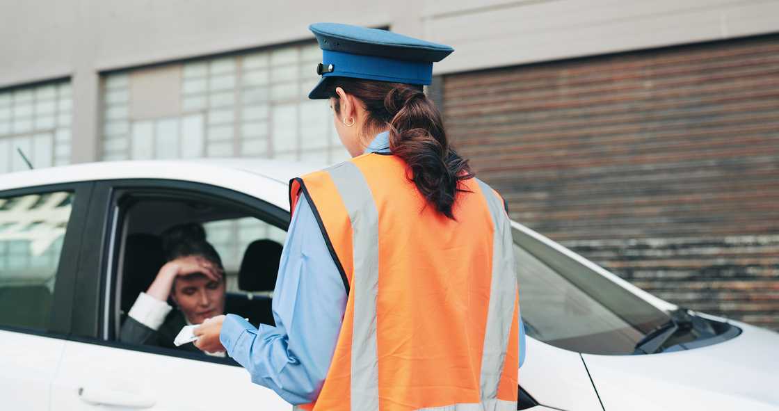 A police officer in the city talking to a driver who has violated law enforcement A police officer in the city talking to a driver who has violated law enforcement