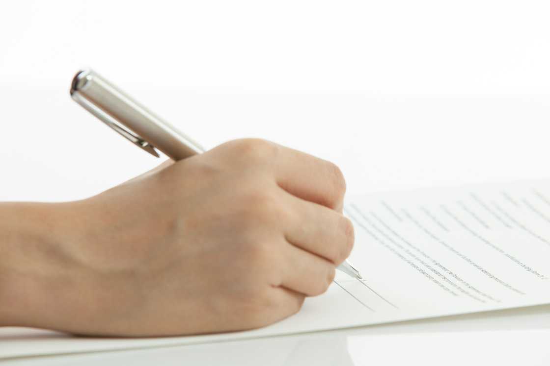 Female hand signing contract on table Female hand signing contract on table