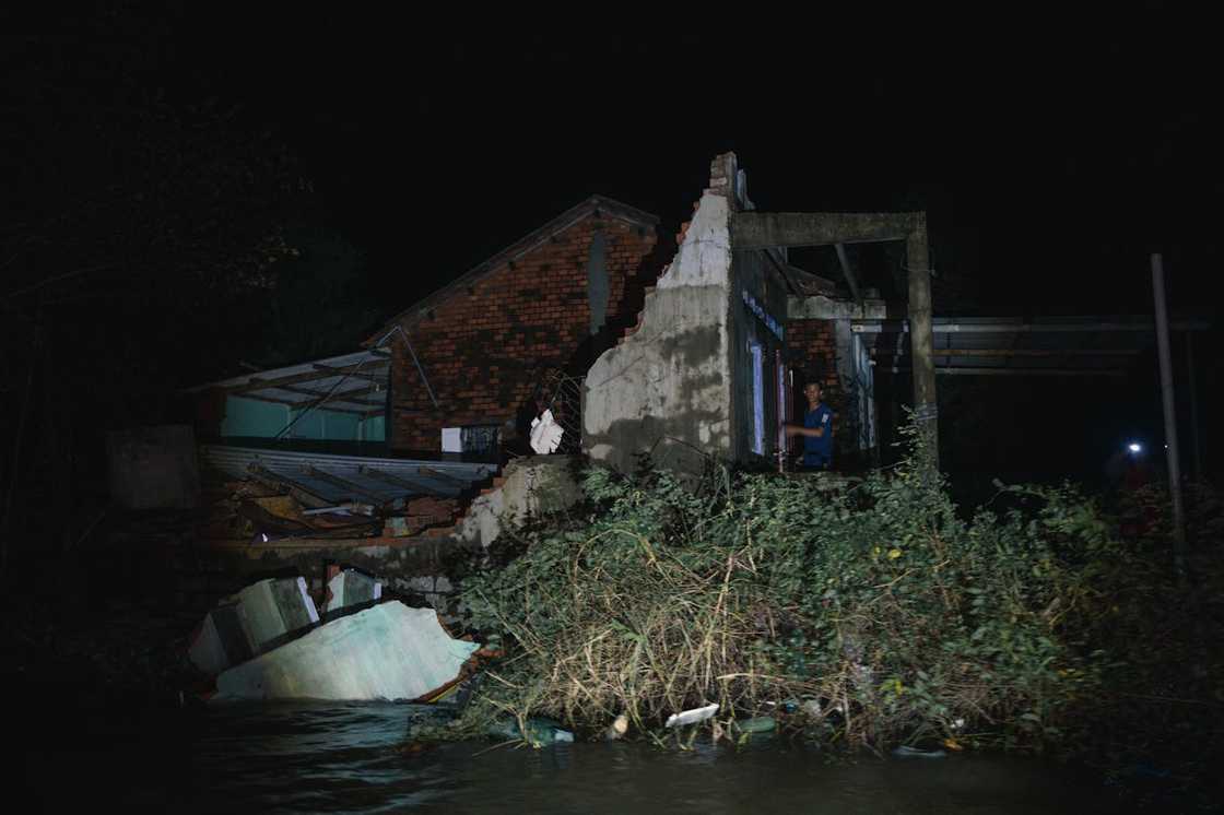 A partially collapsed house stands surrounded by floodwater. A partially collapsed house stands surrounded by floodwater.