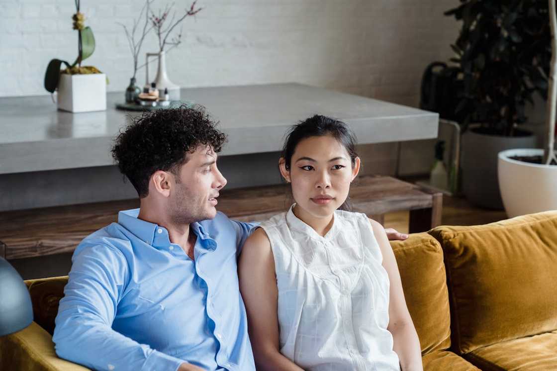 A couple have a conversation while seated in a living room.