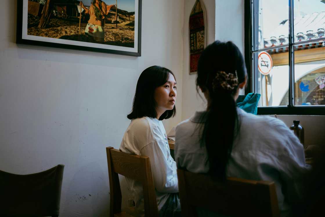 Two girlfriends having dinner; one feeling distressed
