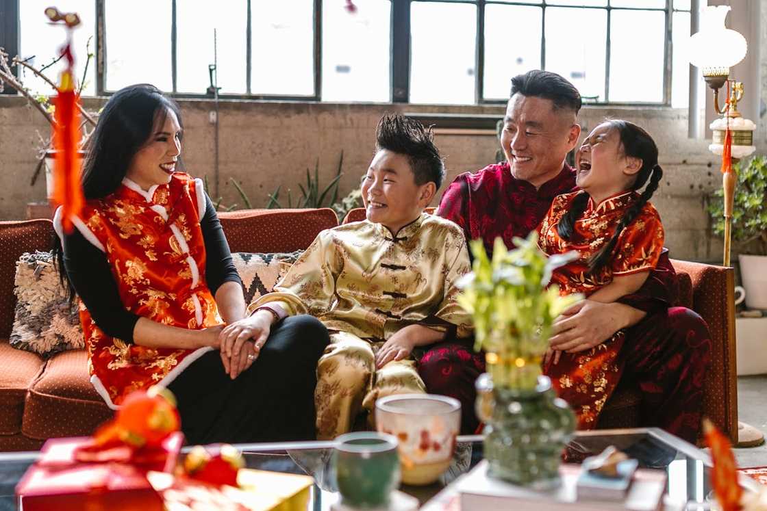 A family of four, in traditional Chinese clothing, sits on a couch.
