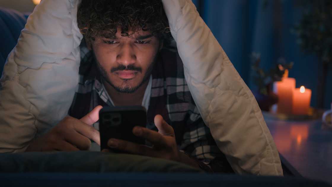 A shocked man looking at his phone at night A shocked man looking at his phone at night