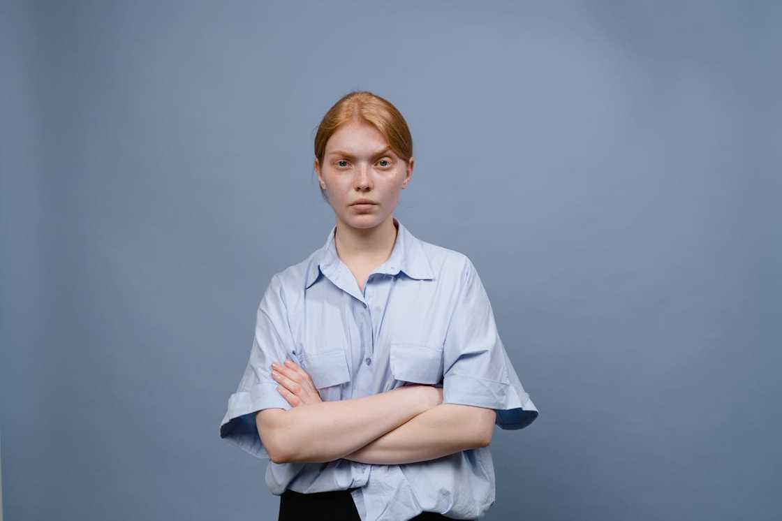 Young woman standing with arms crossed, looking serious.