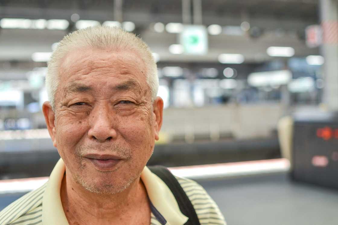 An older person with grey hair smiles.