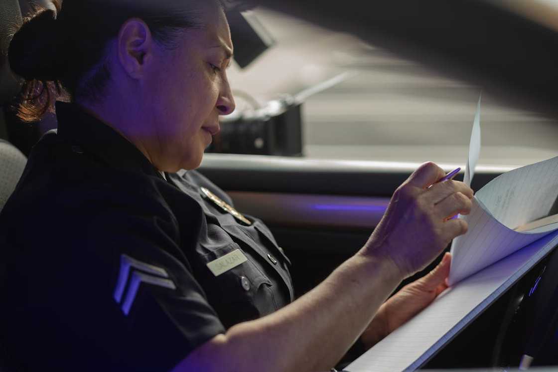 An inspector writes notes inside a car. An inspector writes notes inside a car.