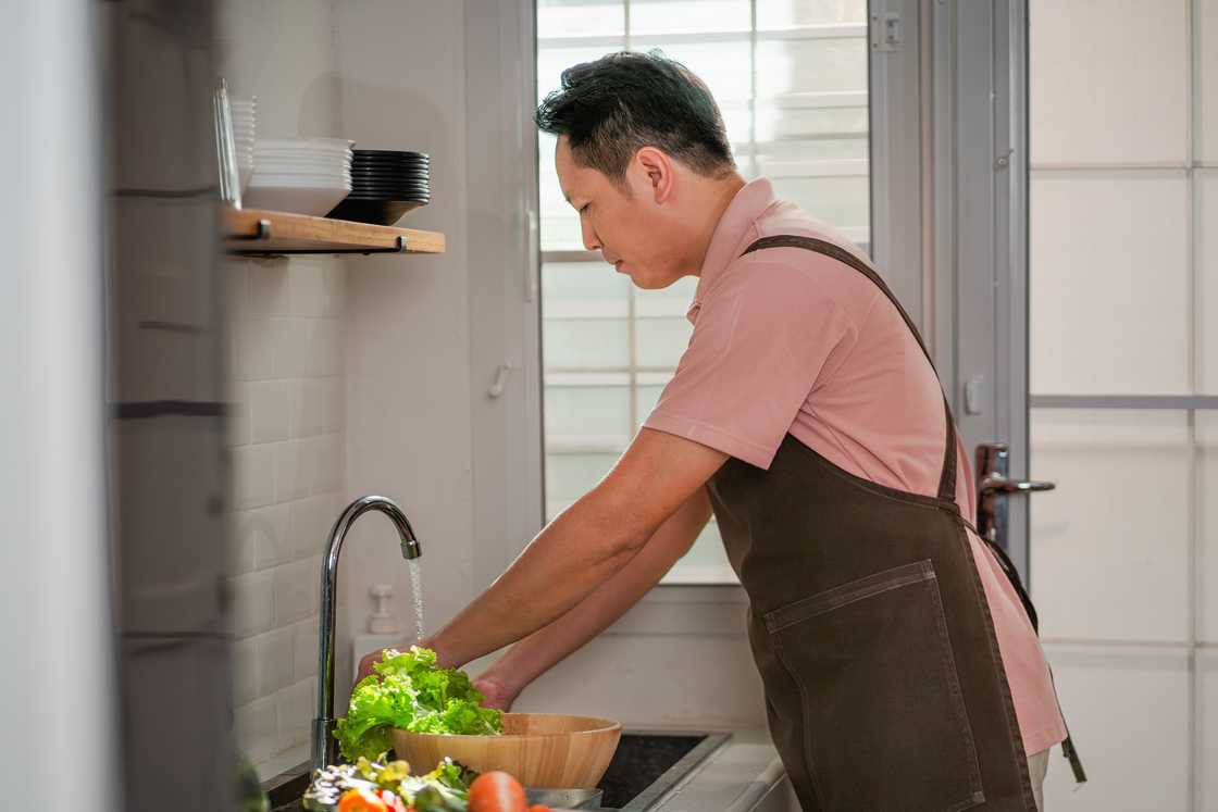 A man washing vegetables in the kitchen. A man washing vegetables in the kitchen.