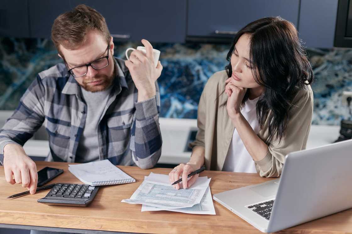 Two adults sit at a wooden table in a bright room. Two adults sit at a wooden table in a bright room.