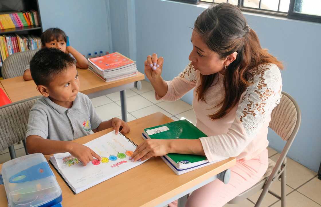 A teacher uses hand gestures to communicate with a student.