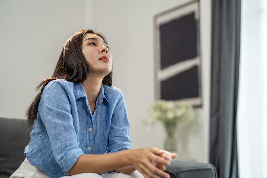 A young woman sitting on a sofa looking up A young woman sitting on a sofa looking up
