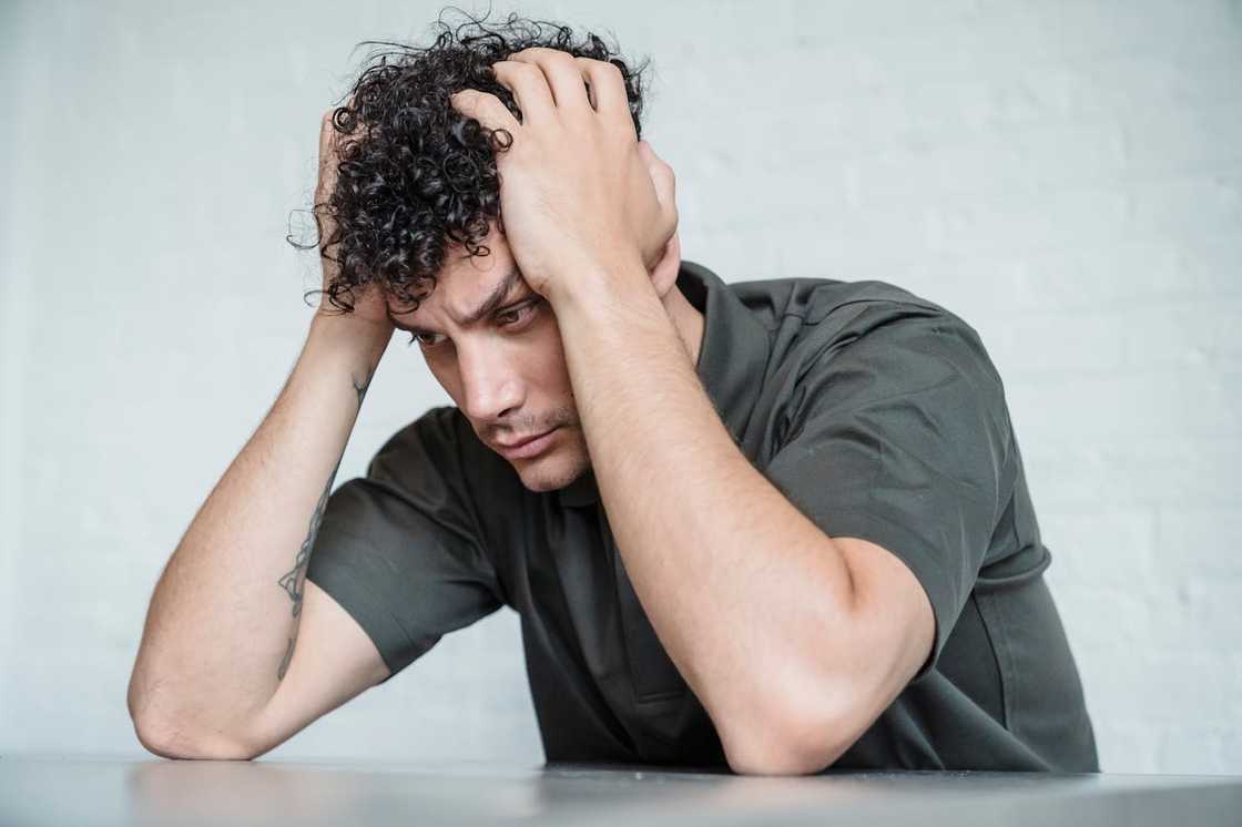 A stressed man thinking with his hands on his head.