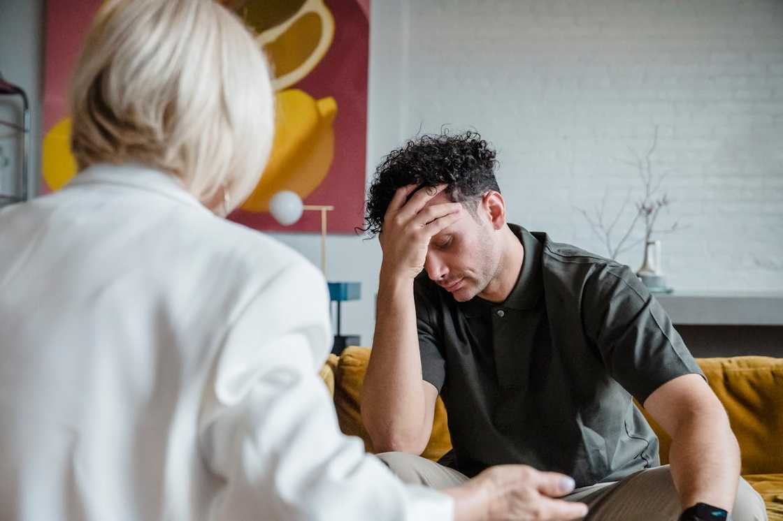A young man holds his head during a therapy session.
