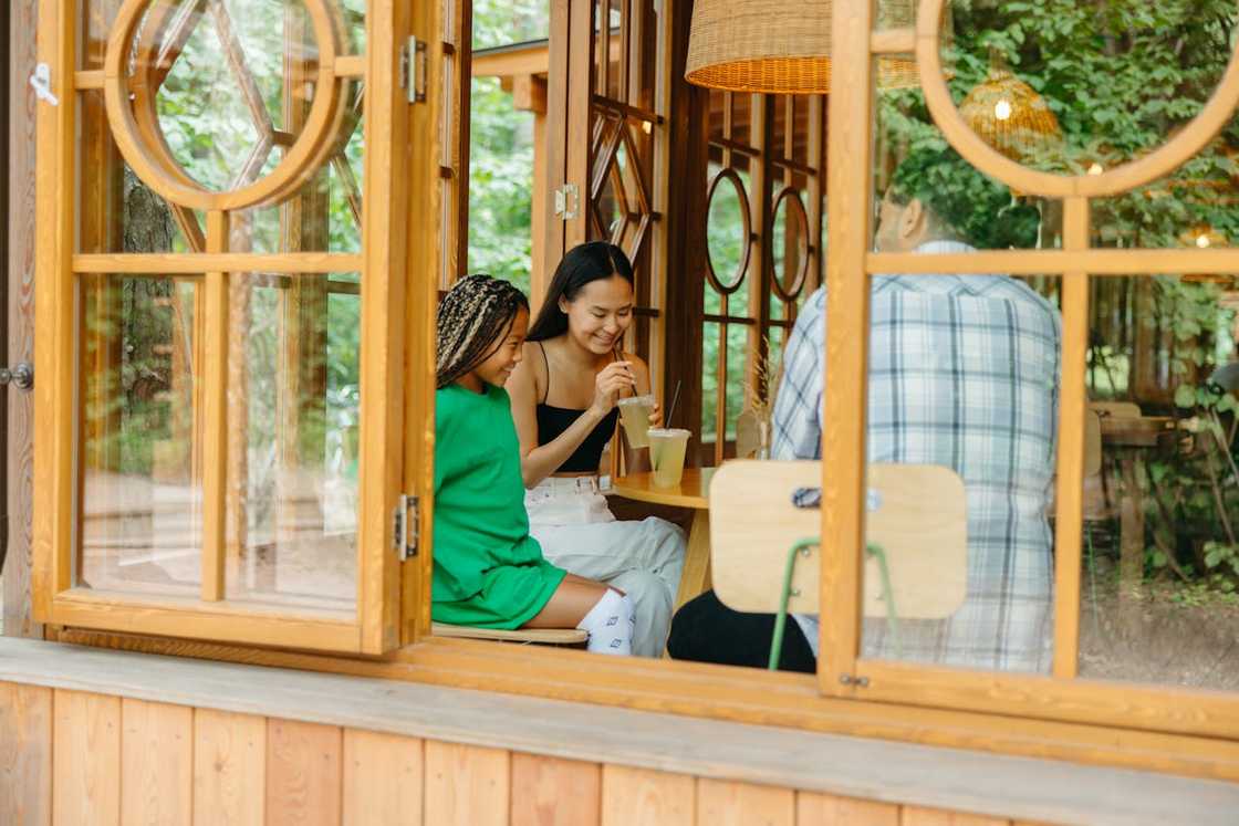 Three people sit in a cosy wooden café.