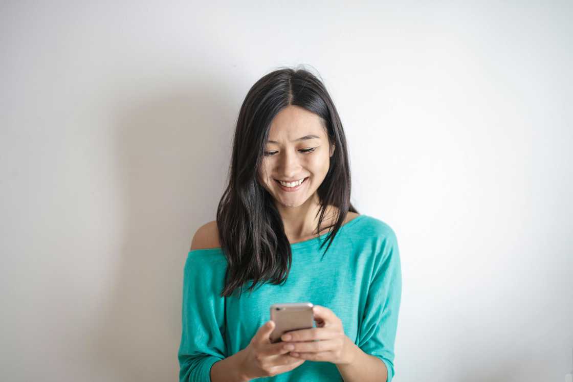 A cheerful woman typing something on a smartphone