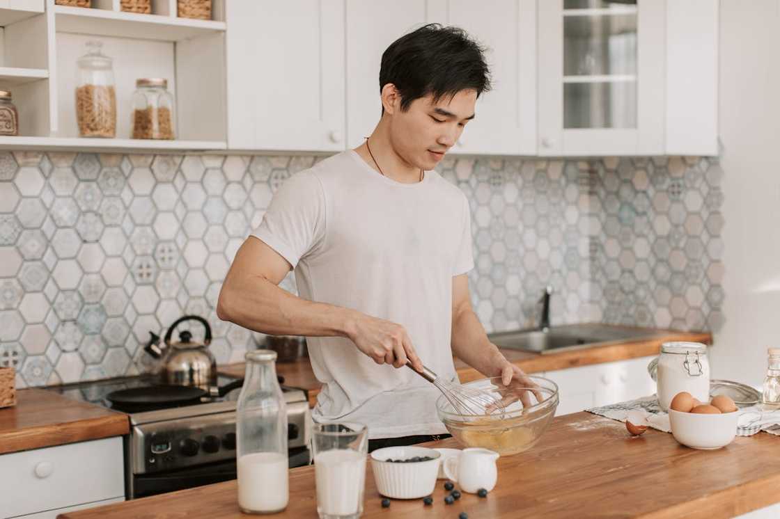 A young man whisks ingredients in a kitchen. A young man whisks ingredients in a kitchen.