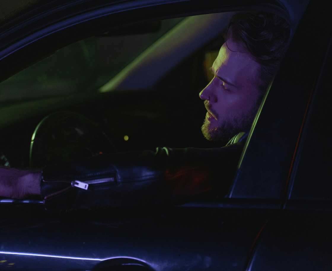 A drunk man in a car at night