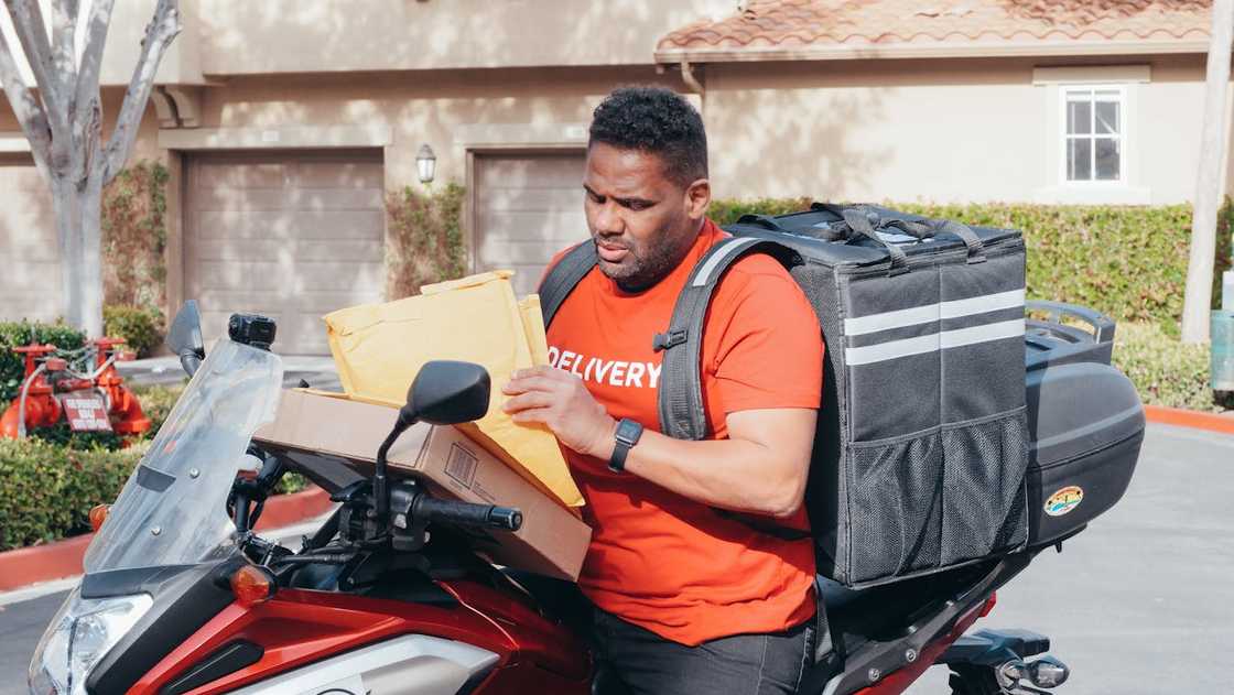 Courier checking parcels beside a motorbike during deliveries. Courier checking parcels beside a motorbike during deliveries.