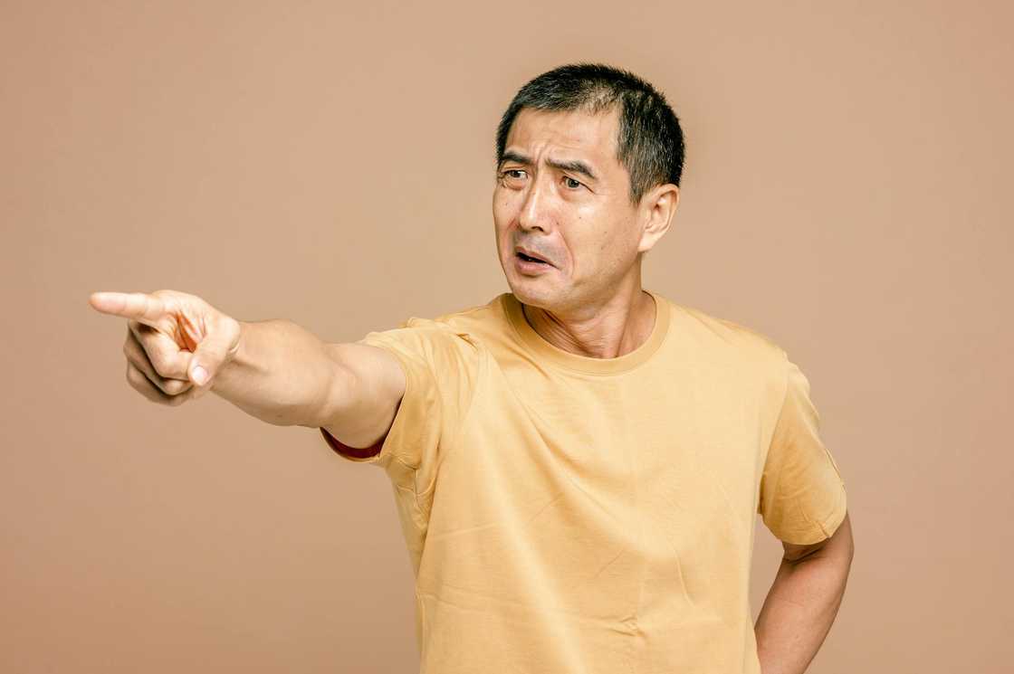 A man in a yellow shirt points forward with an angry expression. A man in a yellow shirt points forward with an angry expression.