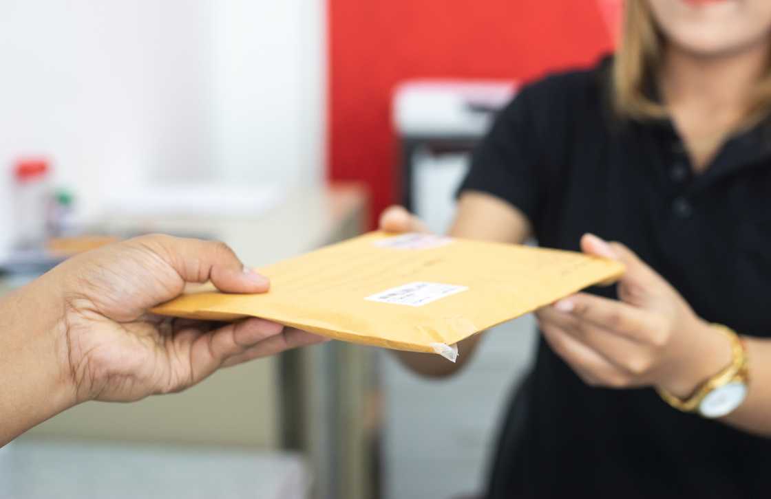 A woman giving out an envelope to a man in an office