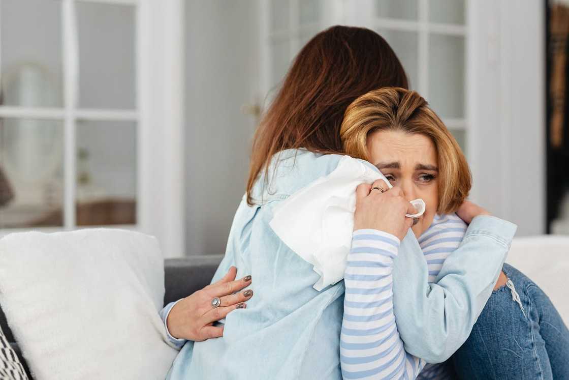 Two sad women hugging indoors. Two sad women hugging indoors.