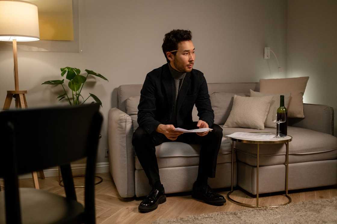 A man reviews paperwork and watches something in a quiet living room.