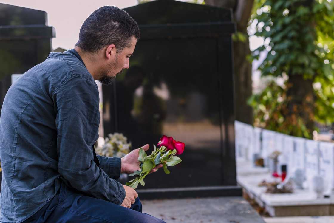 A man holds flowers at a grave A man holds flowers at a grave