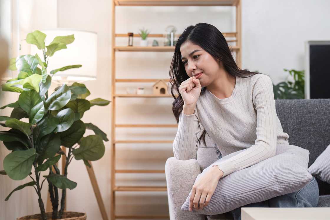 A young woman sitting on a couch thinking