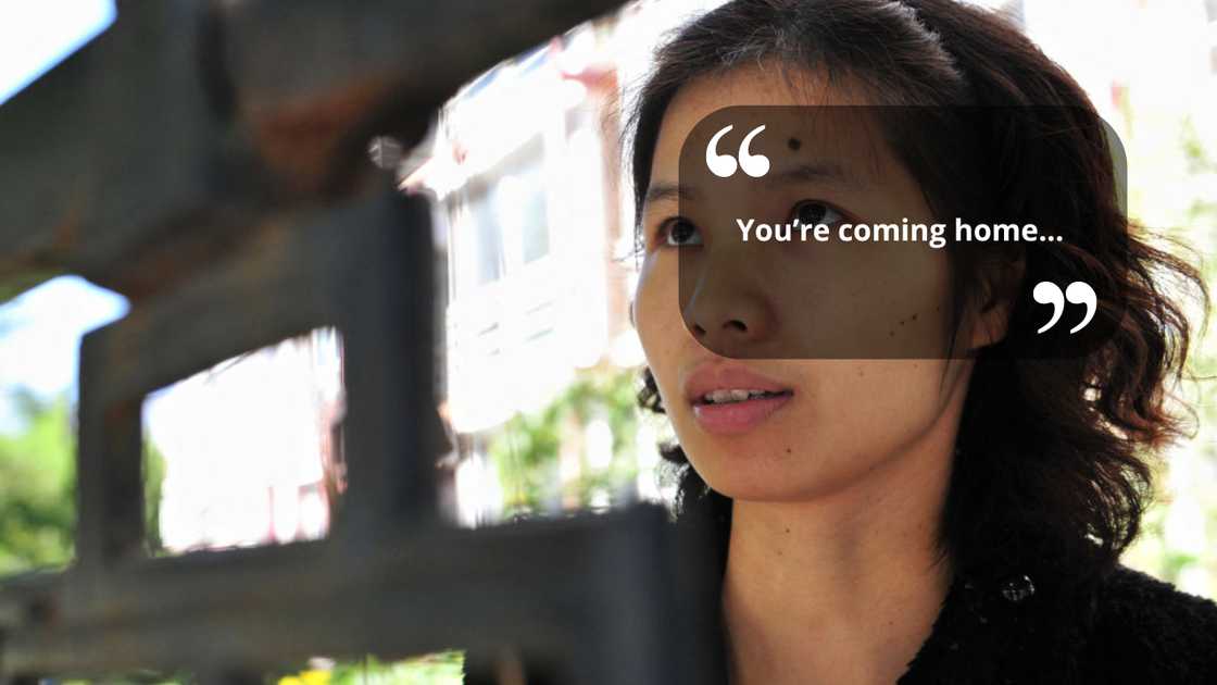 A woman standing outside an iron gate