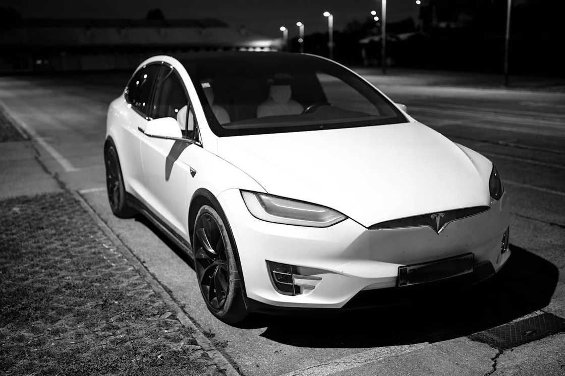 White Tesla Model X parked on a quiet street at night.
