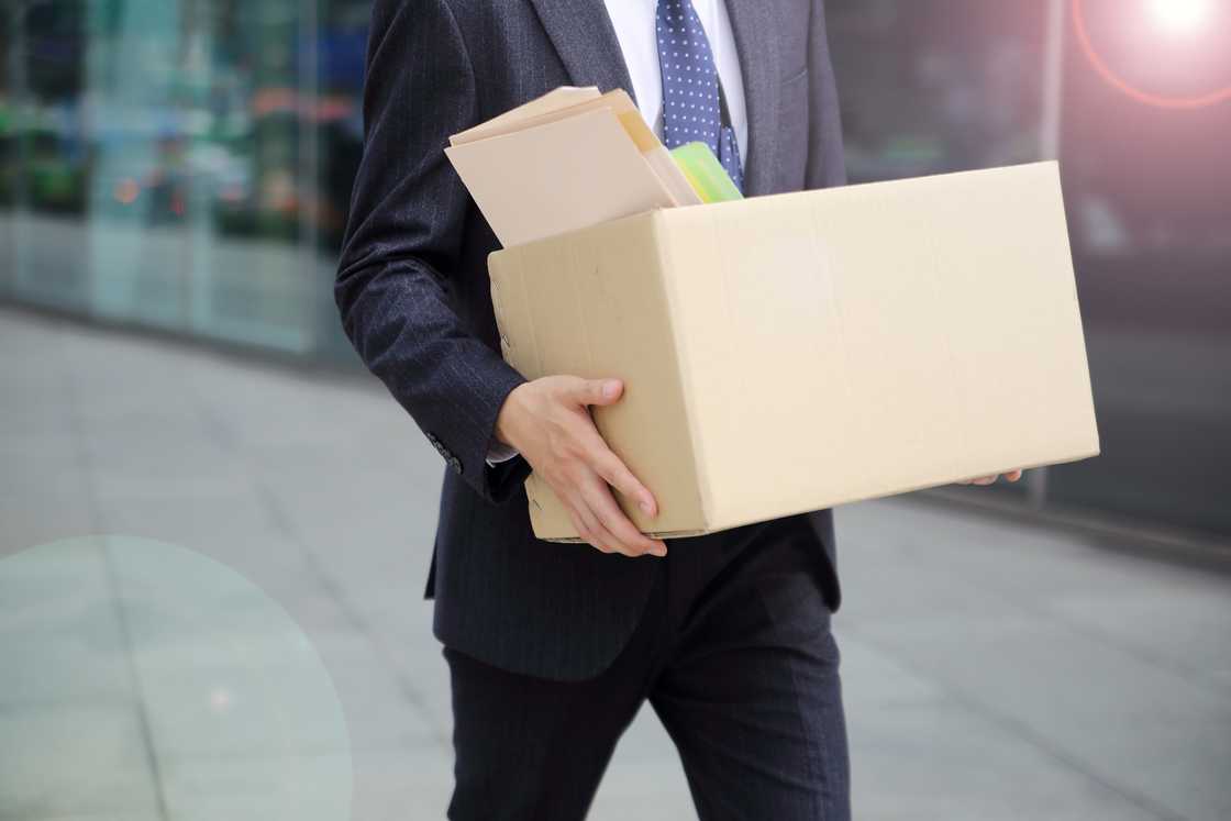 A man carrying a cardboard box of his belongings after being fired A man carrying a cardboard box of his belongings after being fired