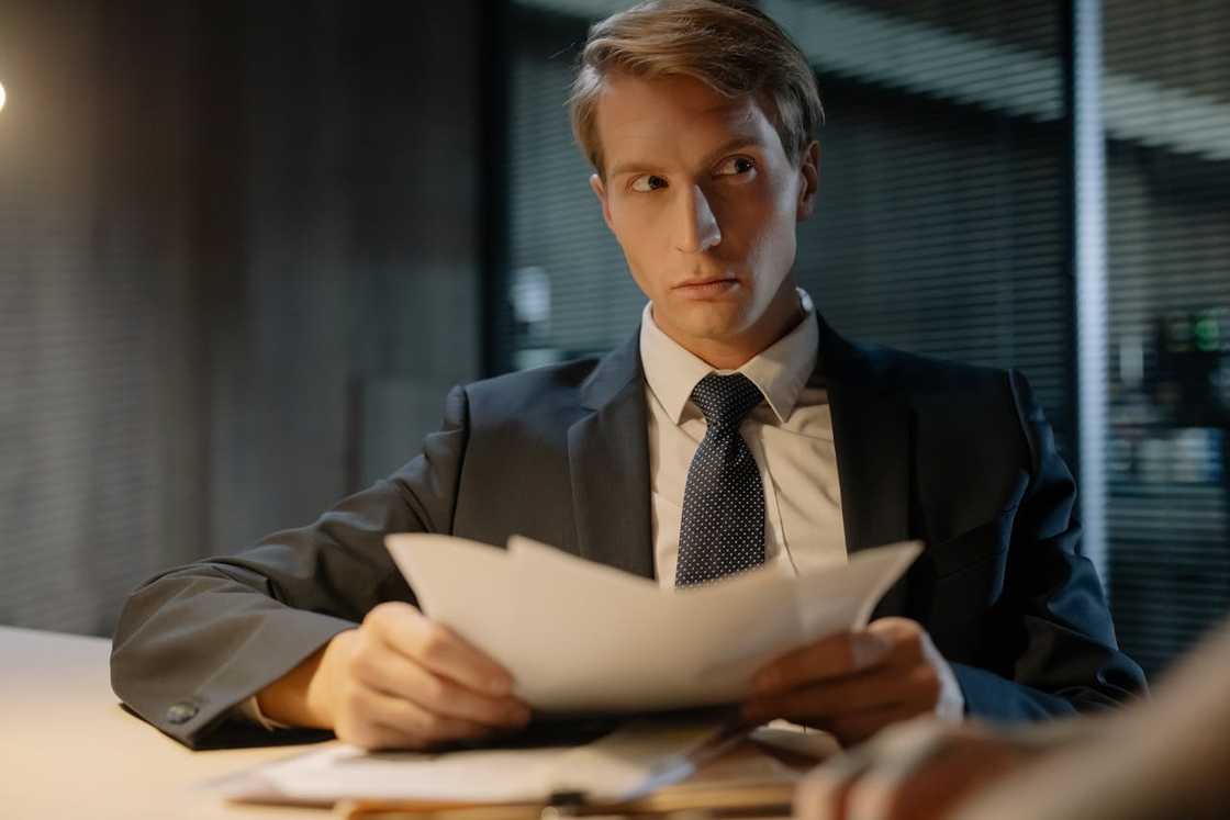 A detective reads papers at a desk. A detective reads papers at a desk.