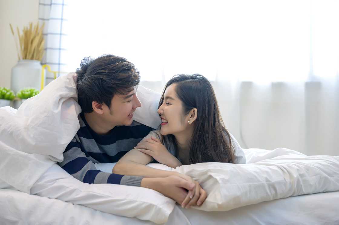 A happy young couple lying down comfortably in their bed