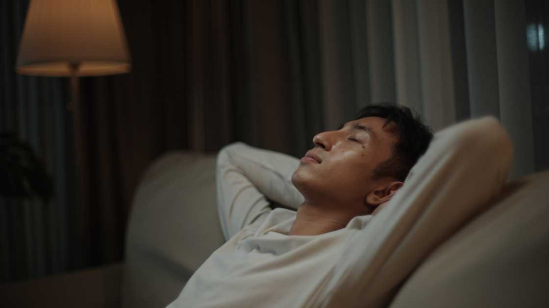 A n exhausted man is lying on the sofa