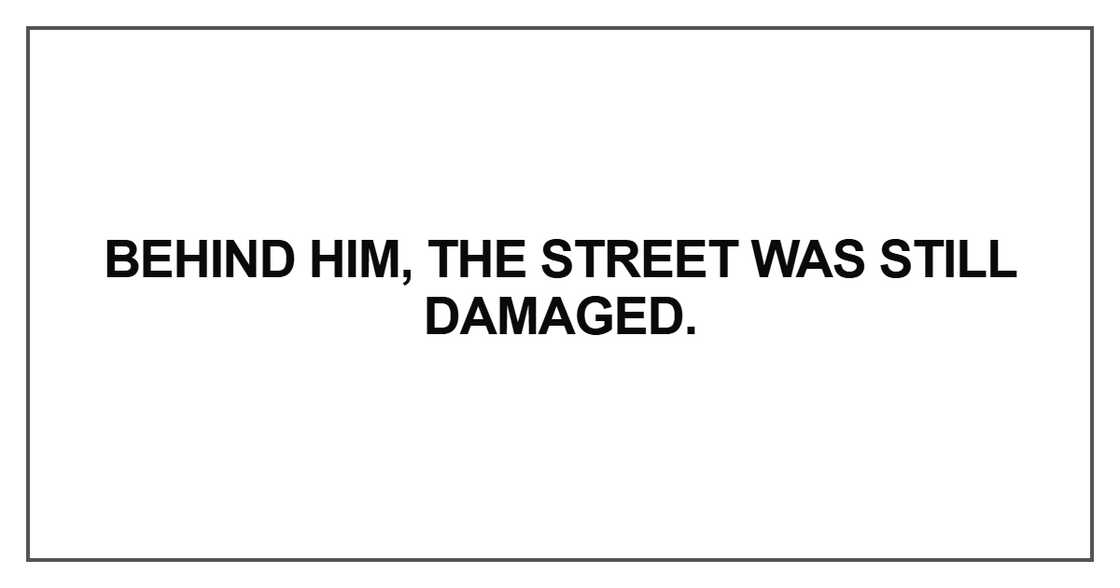 Behind him, the street was still damaged.