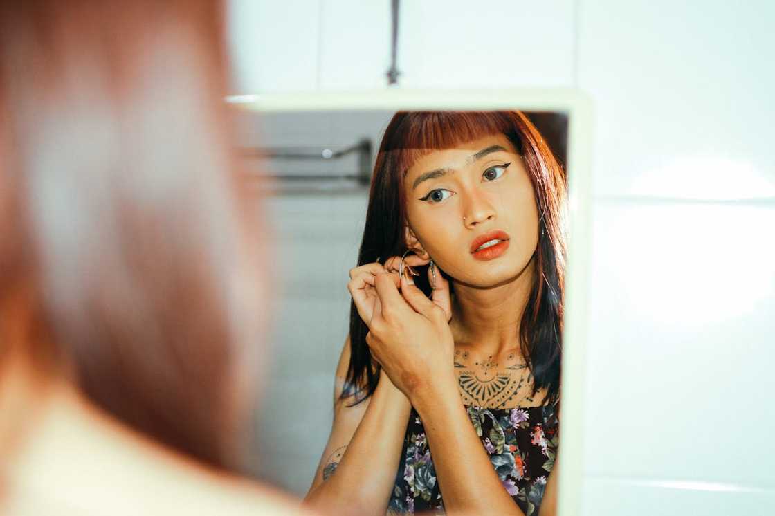 A woman touches her hair, pausing to look at her reflection.
