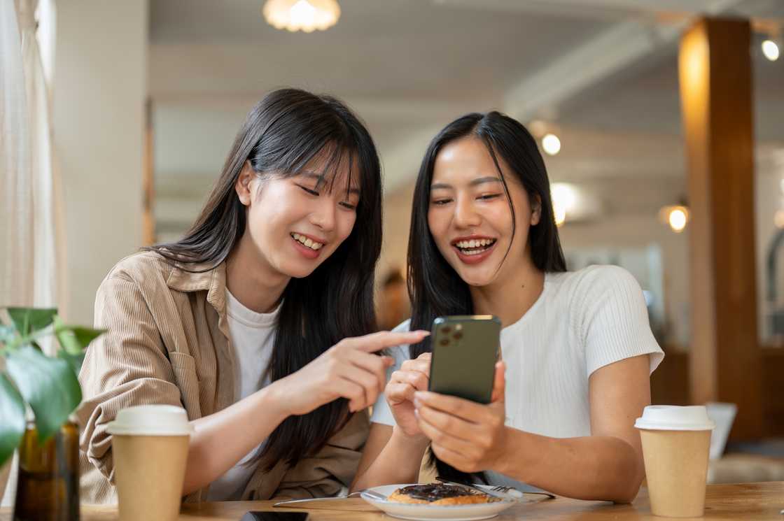 Two ladies at a cafe scrolling on a phone