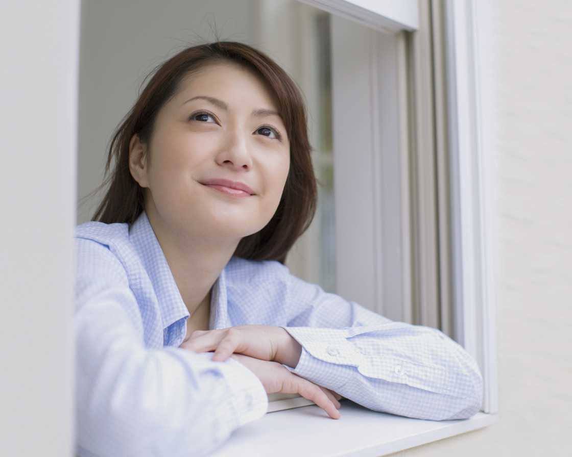 A smiling Young Woman Looking Through Window A smiling Young Woman Looking Through Window