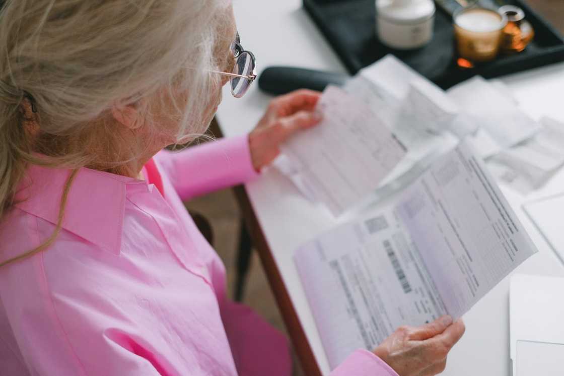 Elderly woman reviewing documents at a desk. Elderly woman reviewing documents at a desk.