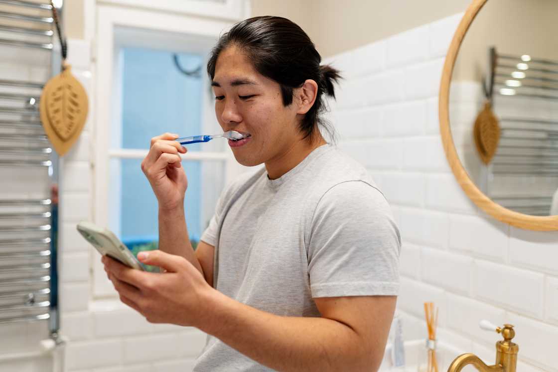 A man is using his phone in the washroom