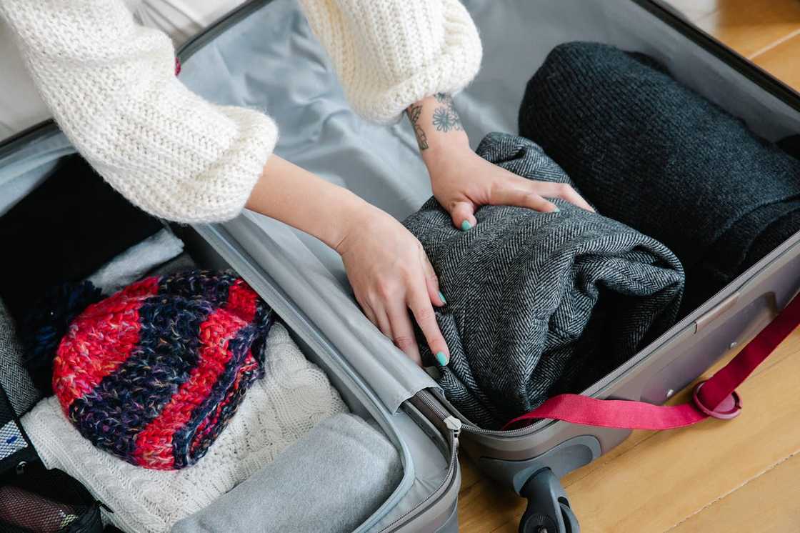 Hands packing folded clothes into an open suitcase. Hands packing folded clothes into an open suitcase.