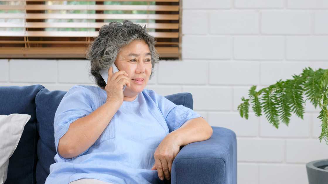 An elderly woman is talking on the phone