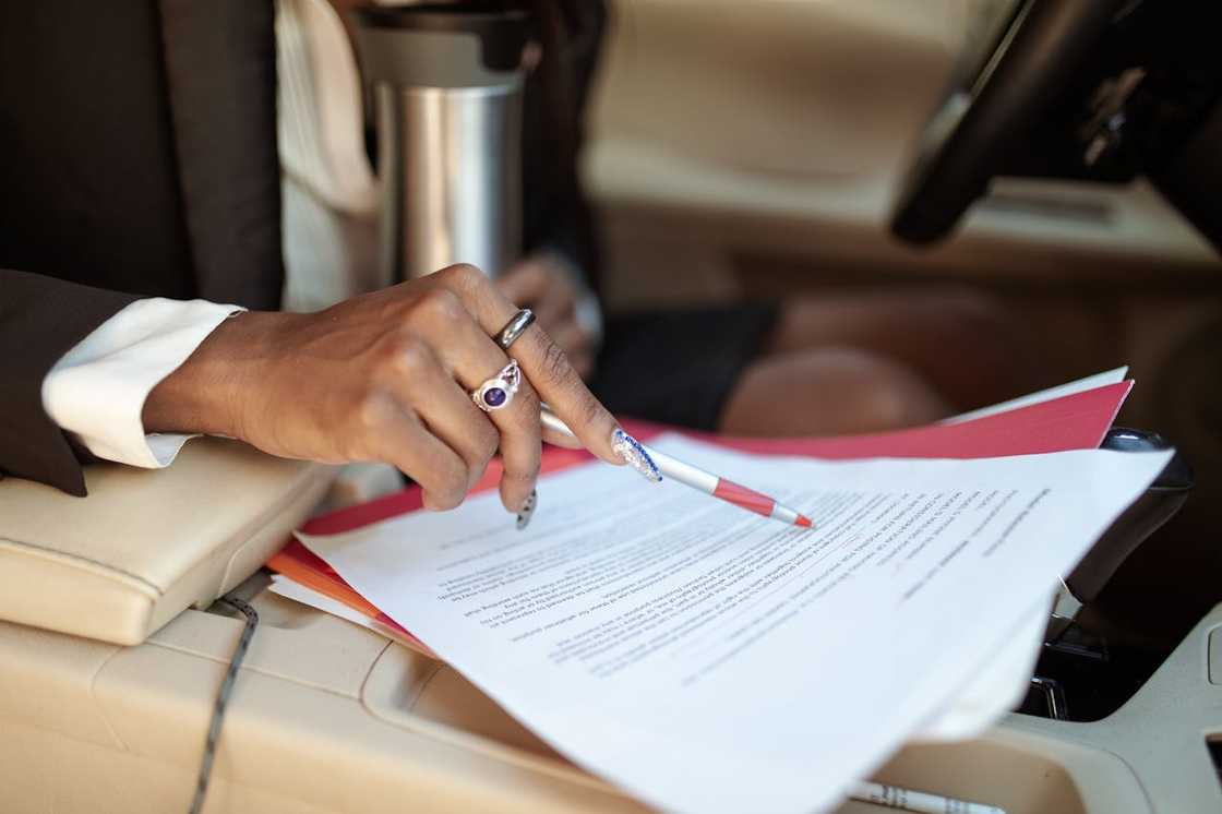 A woman points at a document while reviewing paperwork in a car.