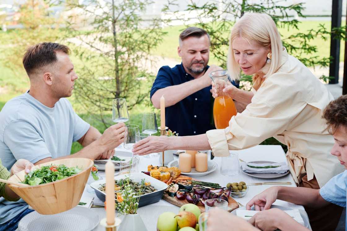 A family shares a meal at an outdoor dinner table.