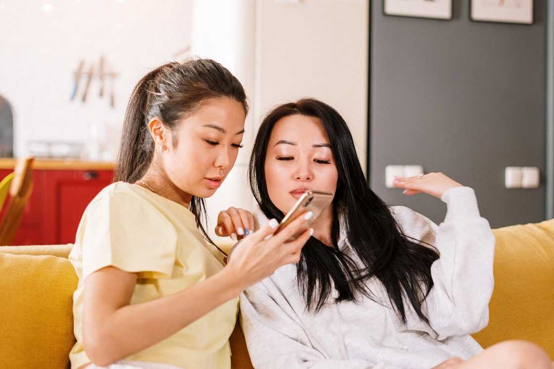 Two women on a couch looking at a smartphone. Two women on a couch looking at a smartphone.
