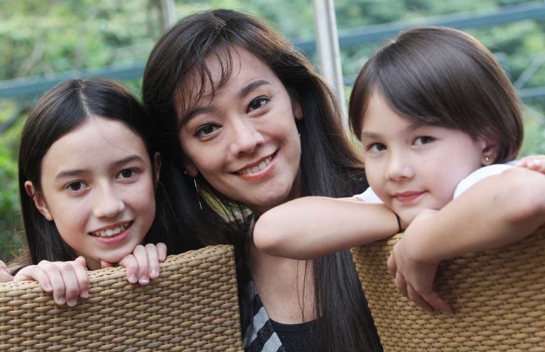 A mother and her twin daughters embracing each other