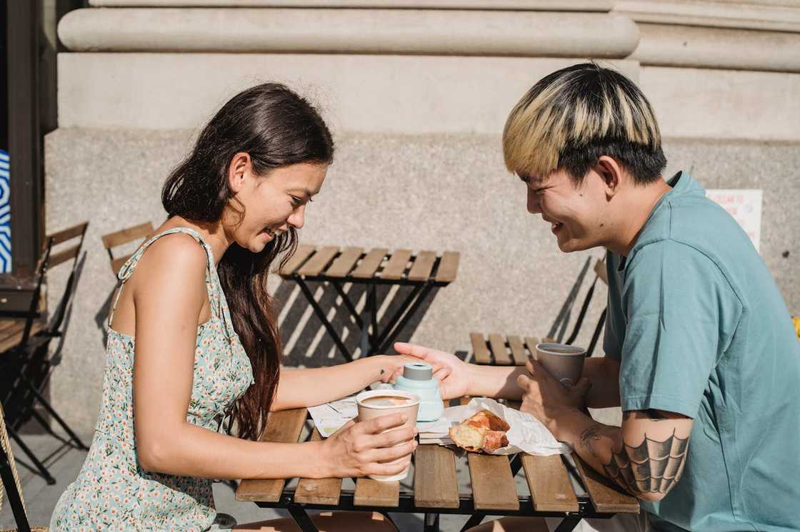 Two people smiling and sharing coffee at an outdoor café table.
