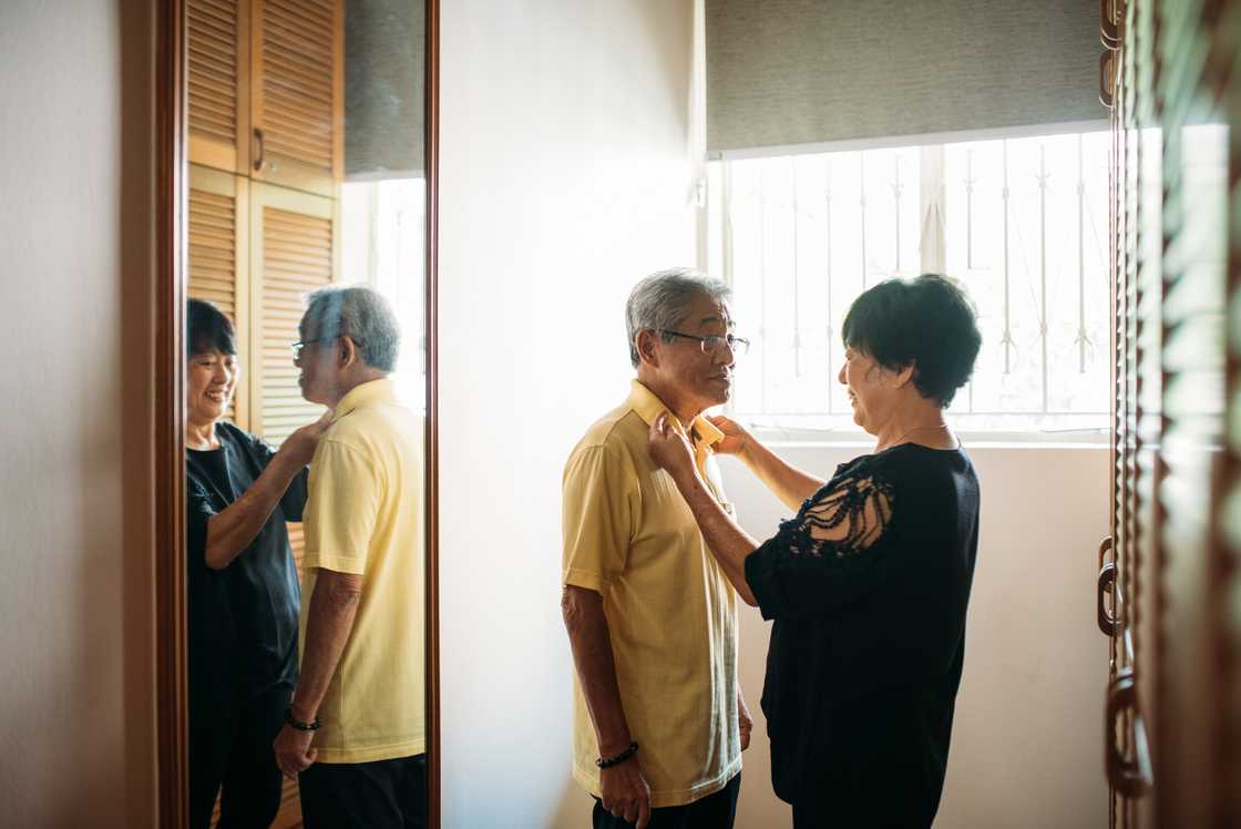 A woman helping her husband to getting dressed