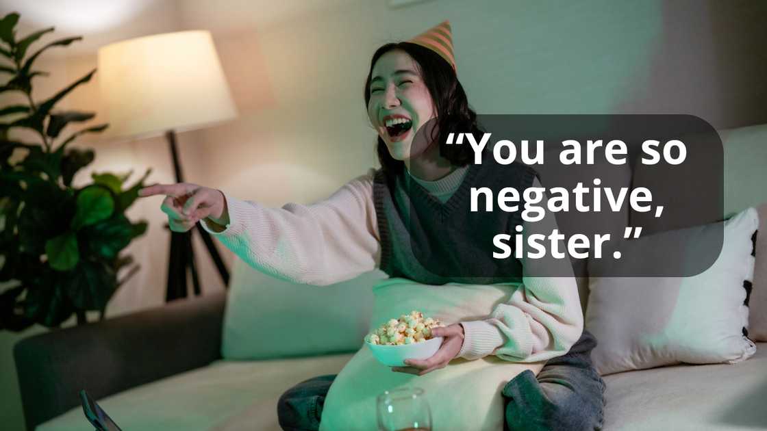 A woman laughing pointing, sitting on a couch, holding a bowl of popcorn A woman laughing pointing, sitting on a couch, holding a bowl of popcorn